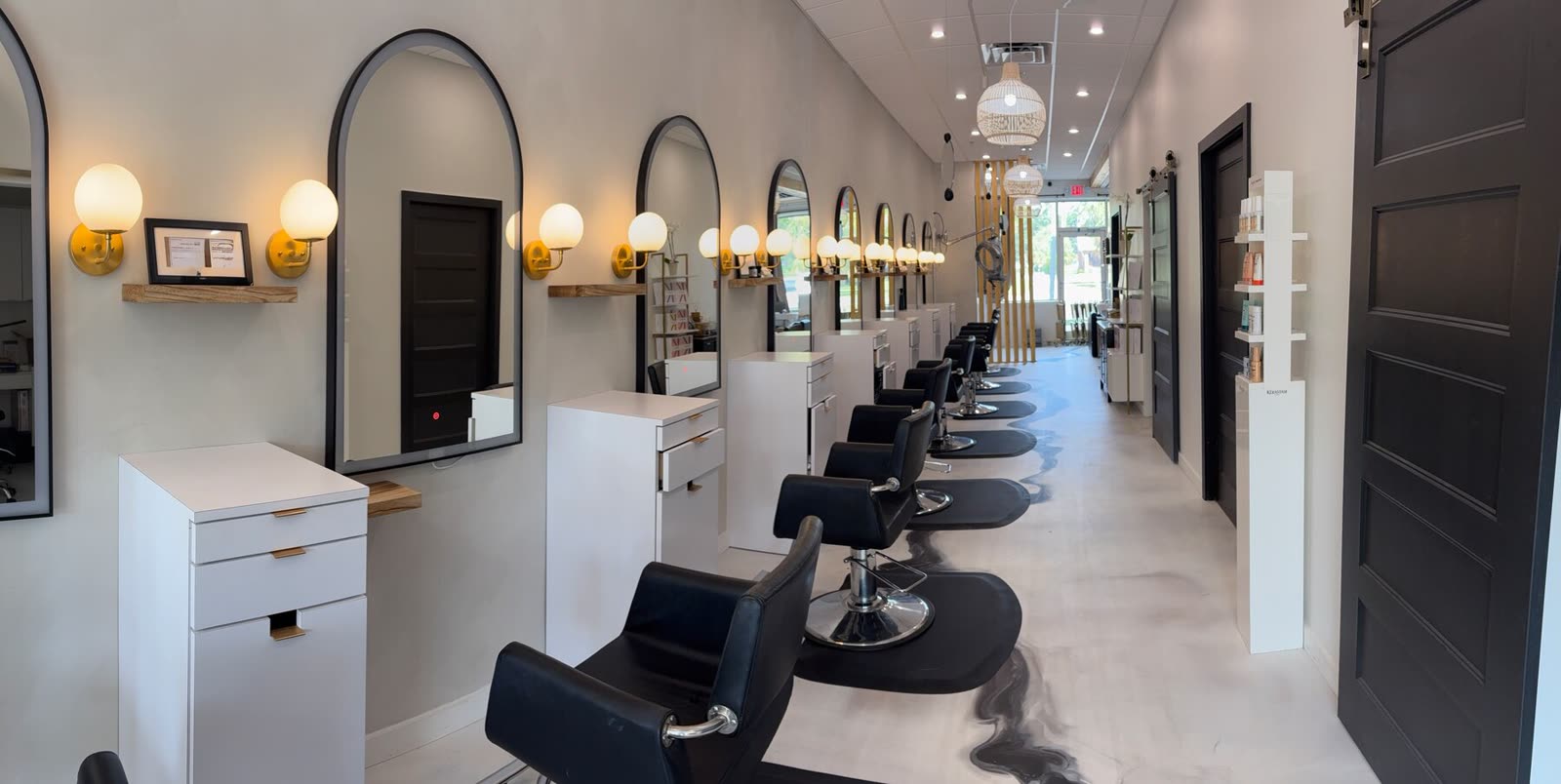 Inside White Sand Salon in Clearwater — the styling chairs, arched mirrors, and gold globe sconces