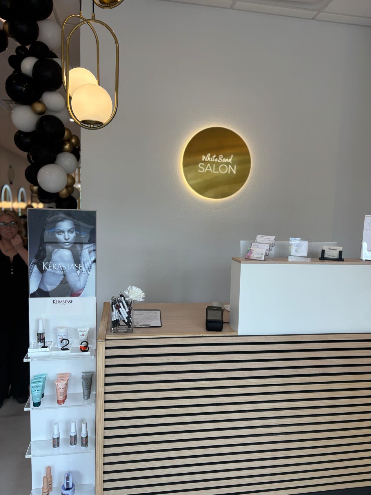 The backlit gold White Sand Salon sign above the reception desk